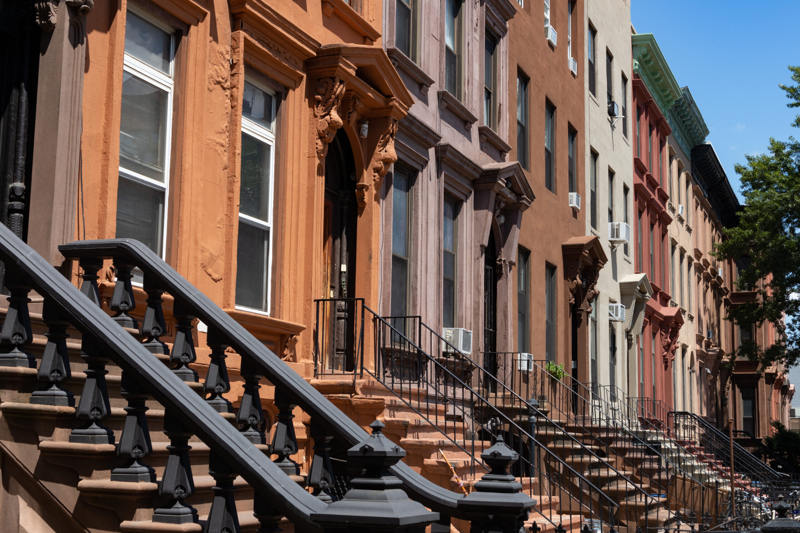 A row of colorful old brownstone homes with staircases in Bedford-Stuyvesant near the Refuge Brooklen
